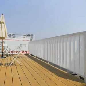 Brise-vue blanc posé sur la rambarde d'une grande terrasse en bois
