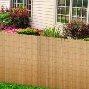 Canisse en roseau installée le long d'un muret de jardin fleuri